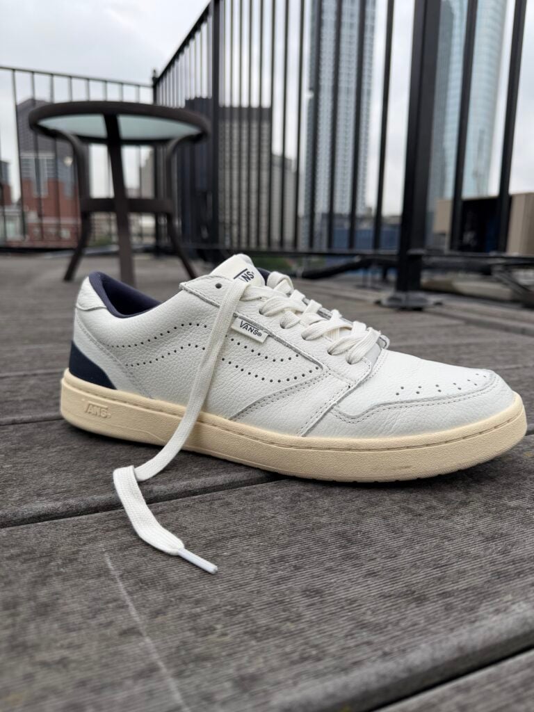 Close up of the the Men’s Vans Court Low Shoe leather white and navy blue with an offwhite outsole profile view
